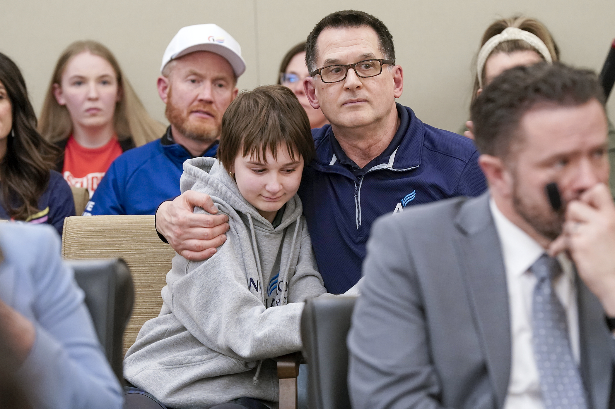 Harry Kaiser, a gym teacher at Annunciation Catholic School, embraces his daughter Lydia following his testimony before the House Public Safety Finance and Policy Committee Feb. 24 in support of HF3433 and HF3402. Lydia, an eighth grader at the school, survived gunshot wounds to her head. (Photo by Michele Jokinen)